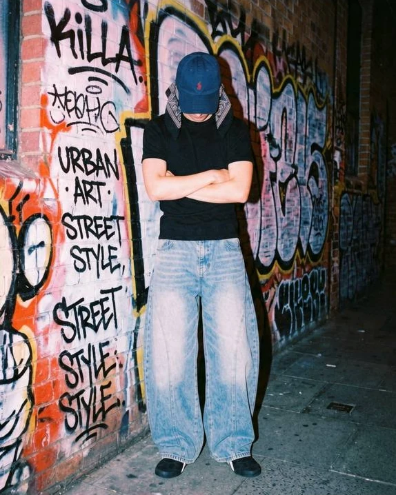 Do Hoang Phi in front of a graffiti wall at night